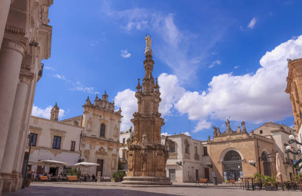 View of the historic centre of Nardò in Apulia, Italy: Salandra Square. In the middle of the square stands the Guglia dell’Immacolata (Immaculate Steeple). The historic centre of Nardò has its heart in the baroque  Salandra Square, characterised by several civic and religious monuments, which are really beautiful, built between the 16th and the 18th century.  In the middle of the square stands the Guglia dell’Immacolata (Immacolata Steeple), 19 metres high, built in 1769 to thank her to have protected the town from the earthquake. On the column, there are the statues made of Lecce stone, representing San Giuseppe, Sant’Anna, San Gioacchino and San Domenico which frame the Immacolata. In the heart of the historic center of Nardò, Piazza Salandra has always been a meeting place par excellence and fascinates the visitor with its beautiful architecture. Piazza Salandra is one of the most beautiful squares in Puglia, not only for the Baroque buildings and the imposing column with the Spire of the Immaculate Conception but also for the charm of the places that have witnessed the life of the community for centuries. lecce stock pictures, royalty-free photos & images