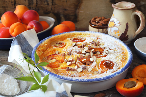 Apricot clafoutis (flan) with almonds, icing sugar dressing, french cuisine, rustic style