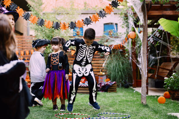 istock Kids Jumping Using Hula-Hoop at Halloween garden party 1339485785