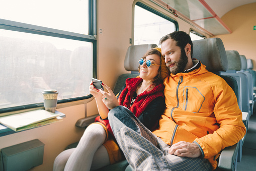 Couple traveling in train and using phone