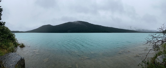 Panoramic image of a glacier fed lake in Canada’s Rocky Mountains on a cloudy summer day