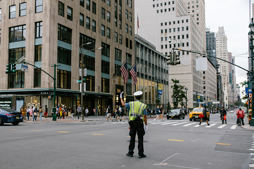 Manhattan, New York, USA - September 5, 2021. A NYPD traffic officer directing traffic in the middle of Fifth avenue in Midtown Manhattan.