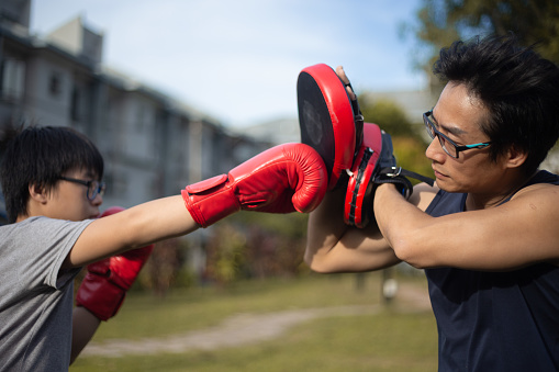 Asian Chinese father and son training kickboxing at backyard outdoor.