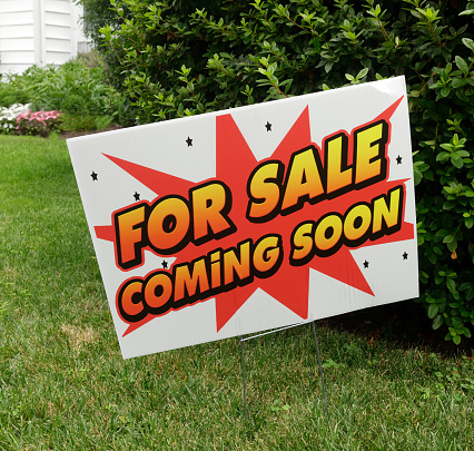 FOR SALE COMING SOON real estate sign on lawn.