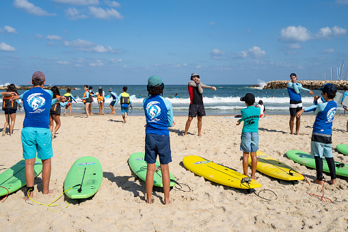 Tel Aviv, Israel - August 18th, 2021:A group of children in a surfing lesson on the Tel Aviv, Israel, beach.