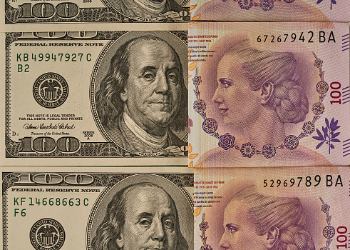 100 Argentine peso bill from Eva Peron observing 100 dollar bill from Franklin