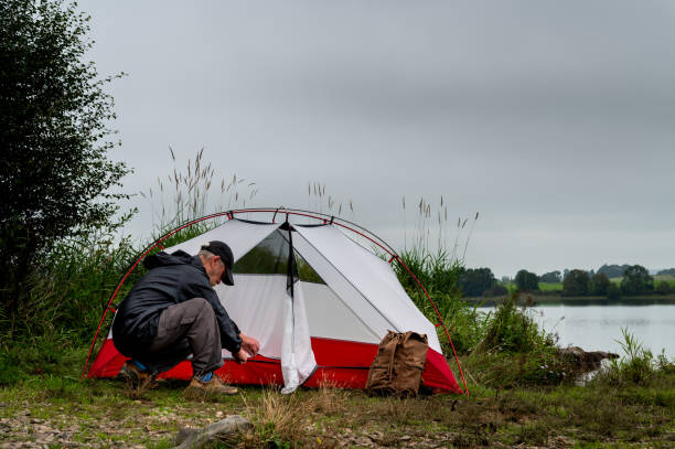 istock Active retired man erecting a tent beside a lake 1339514972