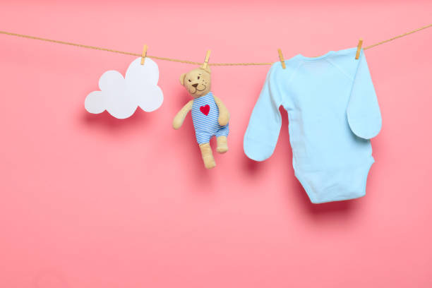 istock Baby clothes on a clothesline on pink background - Image 1339523171