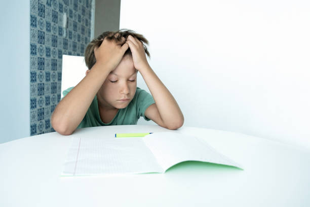 istock Sad boy with book does school homework. Back to school. Unhappy schoolboy with textbooks. Distance learnin 1339527708