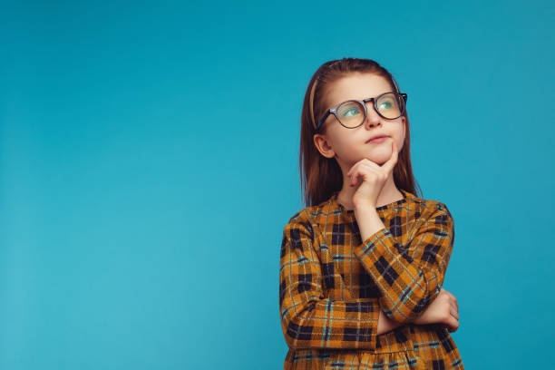 istock Smart girl in nerdy glasses touching cheek and looking up while thinking 1339528891