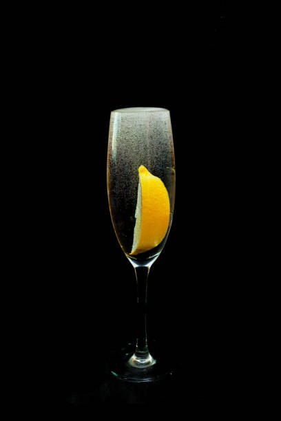 A glass of carbonated drink and a lemon in a black background.