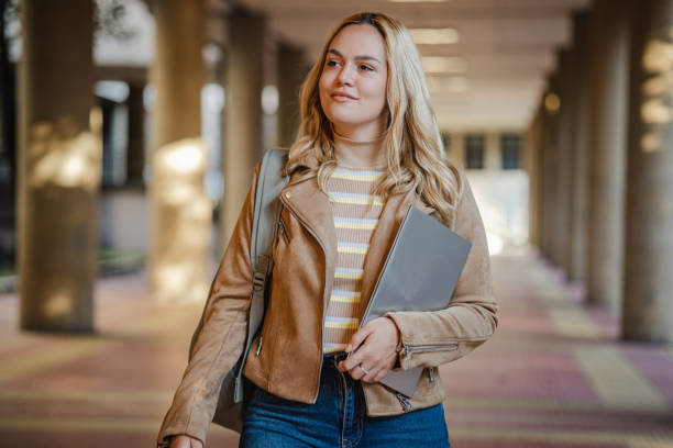istock Young smiling woman walks and carries a laptop in her hand while returning from work 1339532673