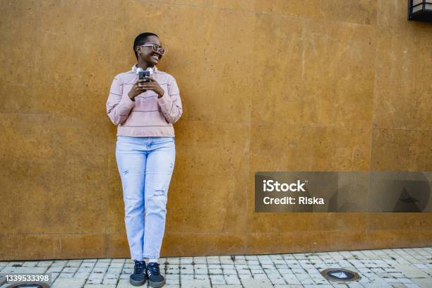 Lifestyle Portrait Of Young Woman Outdoors Stock Photo - Download Image Now - Wide, Wall - Building Feature, One Person
