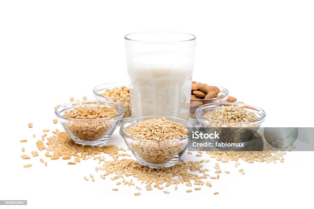 Vegetable milk, ingredients: oats, rice, almonds, soy and khorasan wheat isolated on white background. Vegetable drink in glass cup with assortment of cereals and dried fruits. Soy Milk Stock Photo