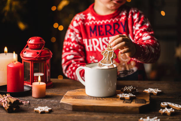 niño sumergiendo galleta navideña de pan de jengibre en taza de leche - christmas child cookie table fotografías e imágenes de stock