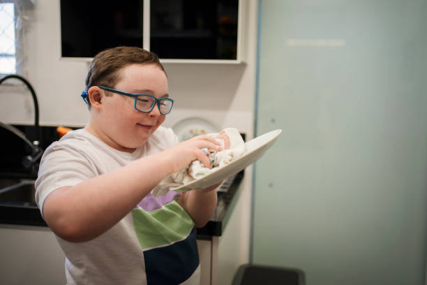 Boy with down syndrome helping with housework. stock photo