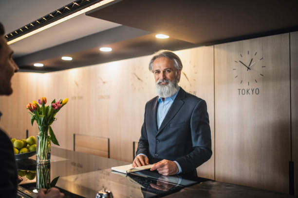 istock Bearded Hotel Receptionist Helping Guest at Front Desk 1339552028