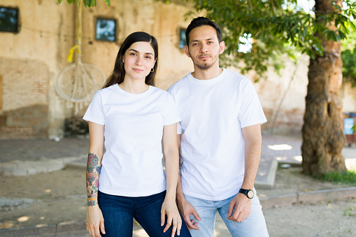 Hispanic young couple with white matching t-shirts making eye contact while spending time outdoors