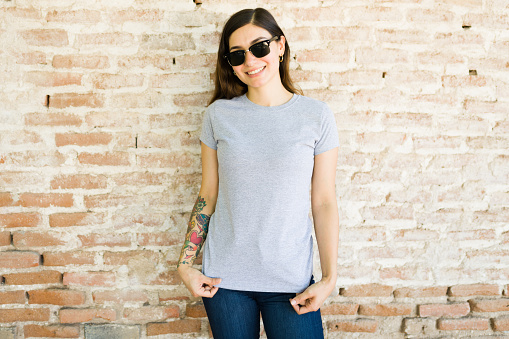 Portrait of a cheerful young woman enjoying a day outside while wearing a gray print t-shirt