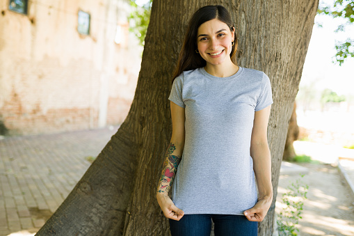 Smiling woman loving her new print t-shirt. Portrait of a young woman wearing a casual gray t shirt
