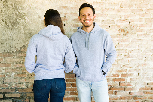 Attractive couple wearing matching gray sweatshirts with a beautiful design in the front and back