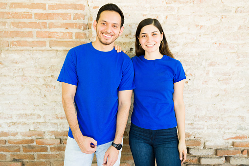 Hispanic young couple with blue matching print t-shirts making eye contact while standing outdoors