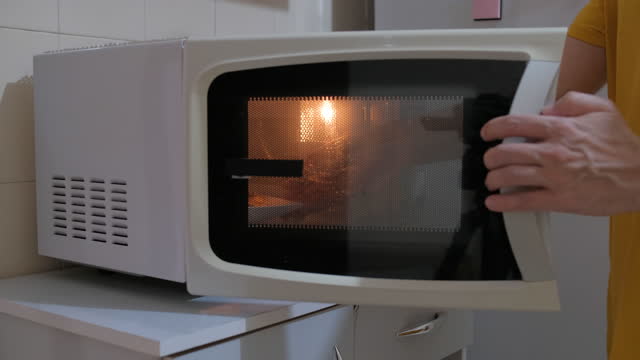 Man putting food to heat in the microwave