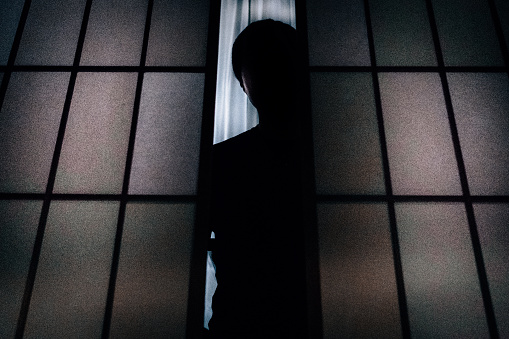 Silhouette of a man who opens the shoji and looks down