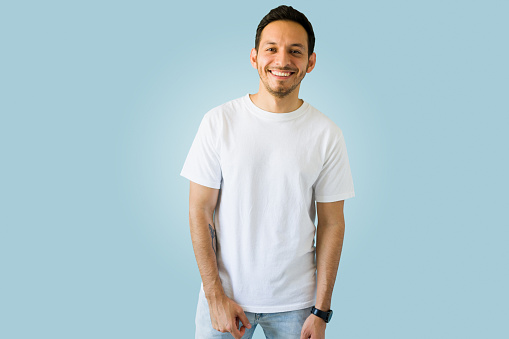 Cheerful hispanic man smiling while wearing a white t-shirt with a print custom design