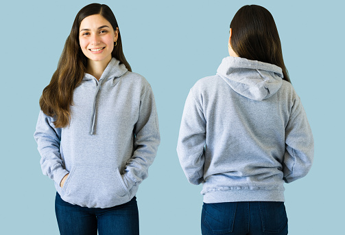 Cheerful young woman in her 20s wearing a gray hoodie with a print design on the front and back