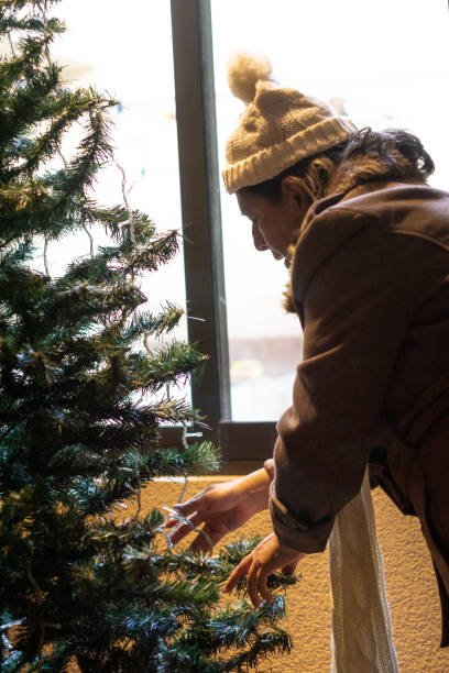 istock a old lady decorating the christmas tree with lights 1339567702