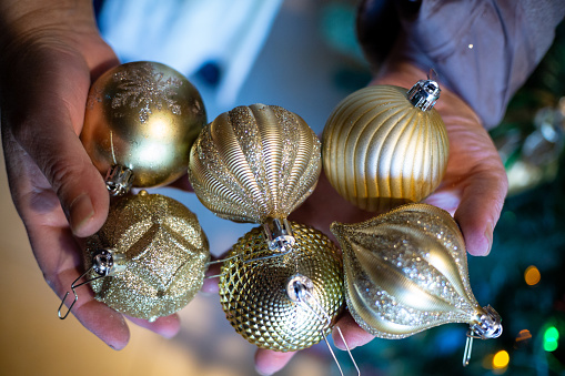 a adult lady hands full of christmas balls for tree decoration