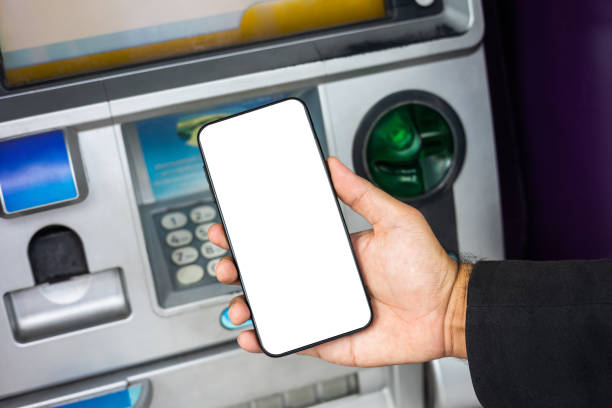 istock Young businessman standing front of atm machine using smartphone withdraw the money without atm credit card. He ut the pin code into smartphone and take the money. 1339578268