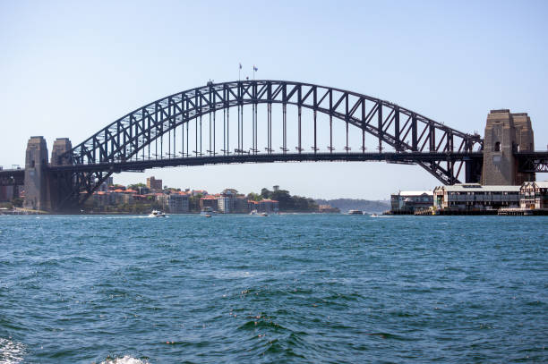 View of Sydney Harbour Bridge from water, Sydney, NSW, Australia The Sydney Harbour Bridge is an Australian heritage-listed steel super bridge through arch bridge across Sydney Harbour that carries rail, vehicular, bicycle, and pedestrian traffic between the Sydney central business district (CBD) and the North Shore. sydney harbour bridge stock pictures, royalty-free photos & images