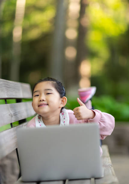niña pequeña usando computadora portátil y pulgares hacia arriba - american sign language student learning real people fotografías e imágenes de stock