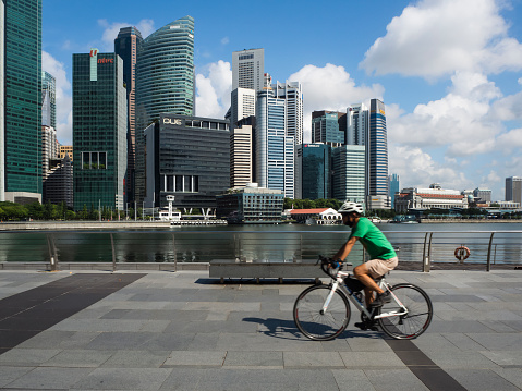 Singapore - August 13 2021: Man cycling in the city along the Singapore River on a sunny day