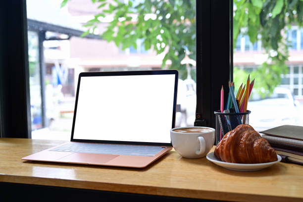 istock Mock up computer laptop with white screen, croissant and coffee cup on wooden table. 1339586676
