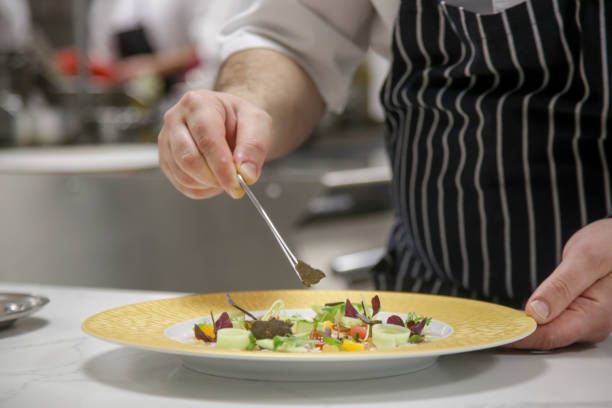 istock Chef in restaurant garnishing vegetable dish. Chef preparing meal in kitchen. Decorating dish, close up. 1339592608