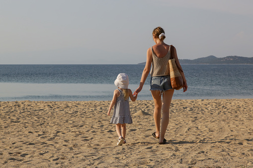 Mother and daughter walking on the beach. Family summer vacation concept.