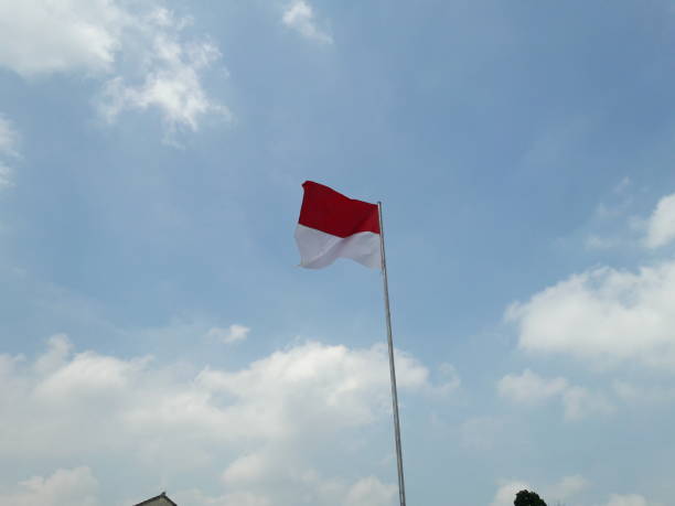 istock red and white flag photo with cloud and sky background 1339607158