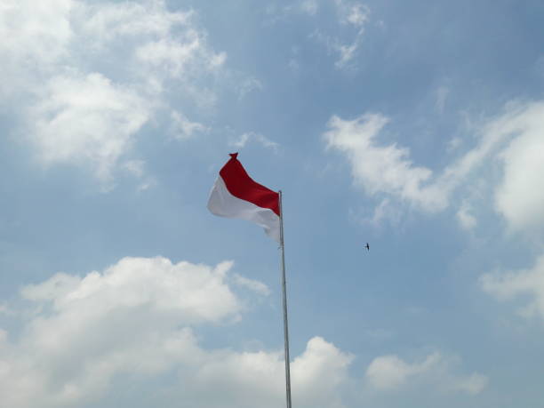 istock red and white flag photo with cloud and sky background 1339607186