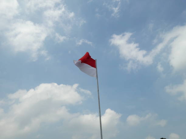 istock red and white flag photo with cloud and sky background 1339607382