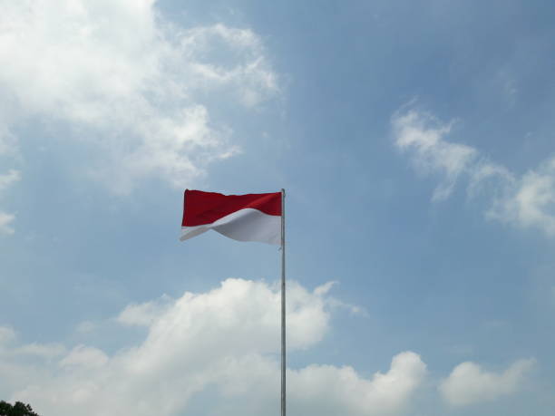 istock red and white flag photo with cloud and sky background 1339607446