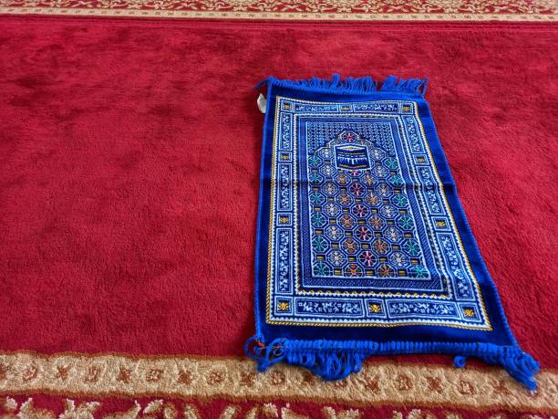 istock Muslim mini prayer rug on red carpet mosque 1339609395