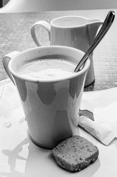 Cup of coffee with milk jug and cookie