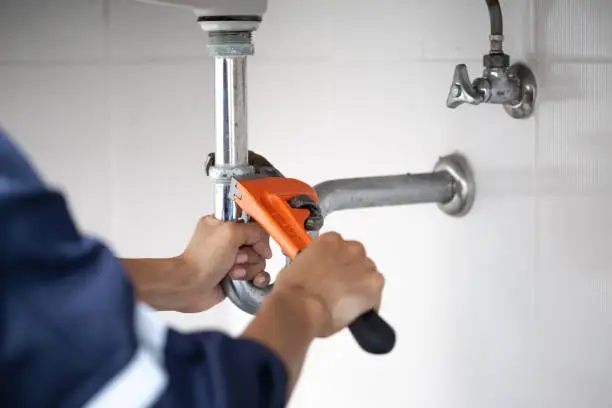 Photo of plumber at work in a bathroom, plumbing repair service, assemble and install concept.