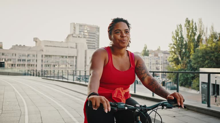 Active lifestyle. Young chubby african american woman enjoying bicycle ride outdoors, cycling in urban area