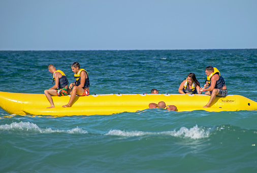 Tourists have fun at sea on the inflatable banana pulled by the skyjet. They fell into the sea. Romania, Jupiter. August, 21, 2021