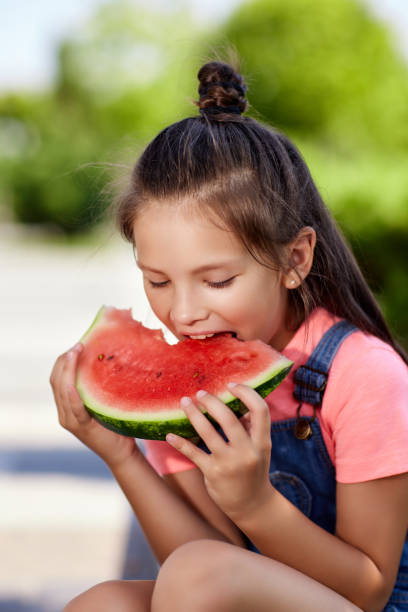 istock child girl eats a watermelon in sunny day 1339621735