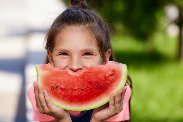 istock child girl eats a watermelon in sunny day 1339621752